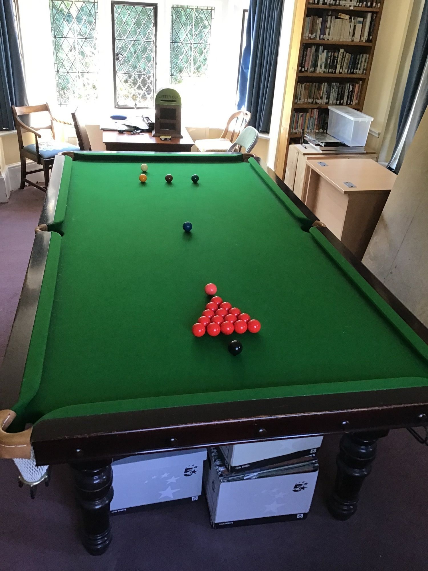 An early 20th century mahogany three quarter size snooker table on six turned tapered legs, unbranded with a set of snooker and pool balls, cues, rests and a Riley score board, length 290cm, width 153cm, height 88cm. Ple
